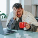 determined-man-conquers-seasonal-afflictions-his-cozy-home-office-with-duvet-laptop