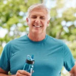 fitness-garden-senior-man-with-water-bottle-exercise-hydrate-retirement-health-nature-workout-happy-elderly-guy-from-canada-with-smile-standing-outdoor-park-summer-day