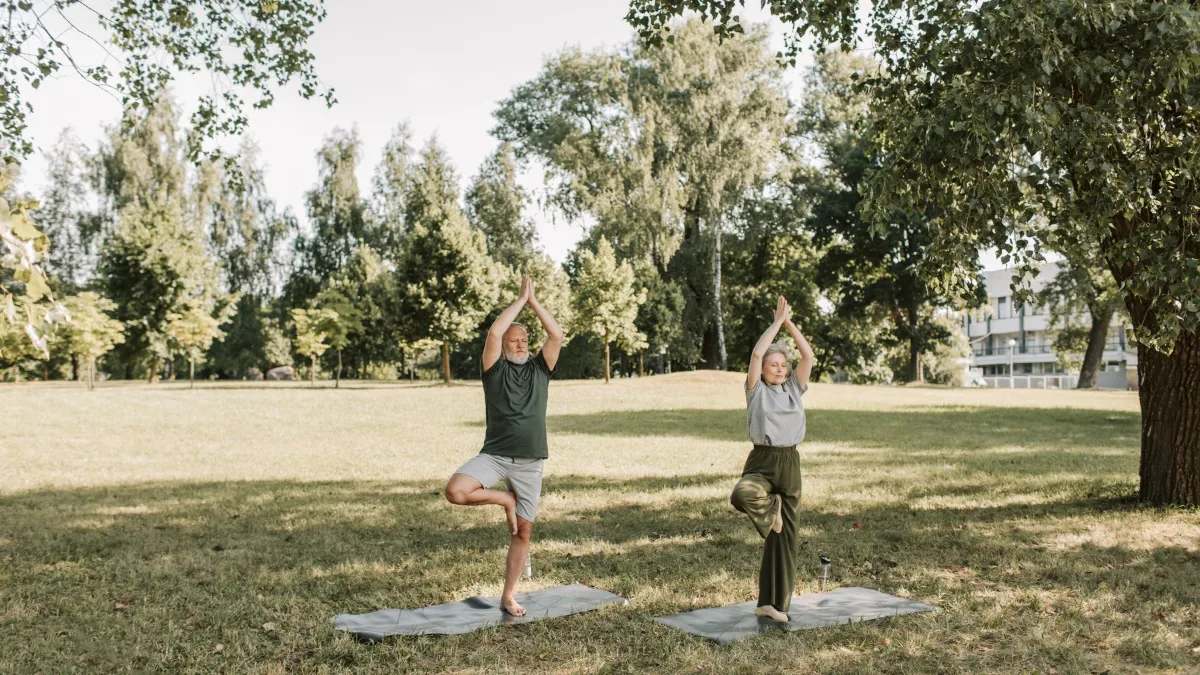 Older couple practicing a standing balance pose in a park
