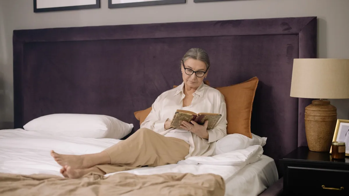Older woman reading a book in bed in the evening