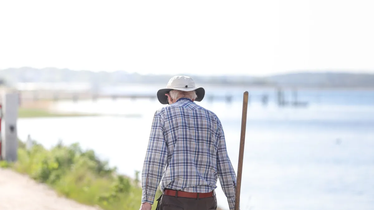 Retired man in a sun hat walking along a coastal path