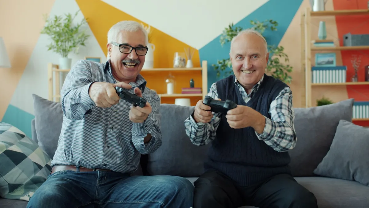 Two older friends laughing together on a sofa