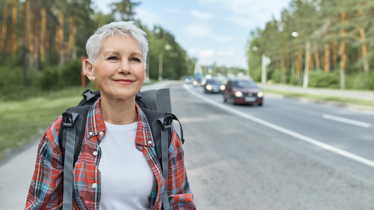 woman carrying backpack walking along-high road