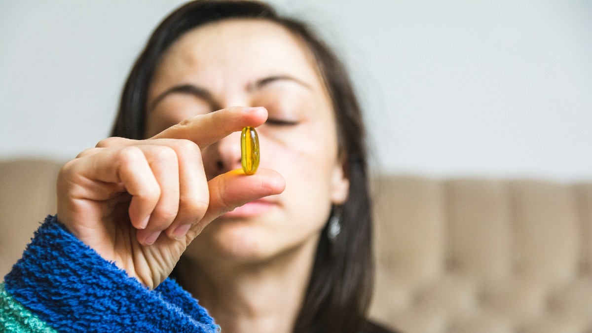 woman holding yellow pill